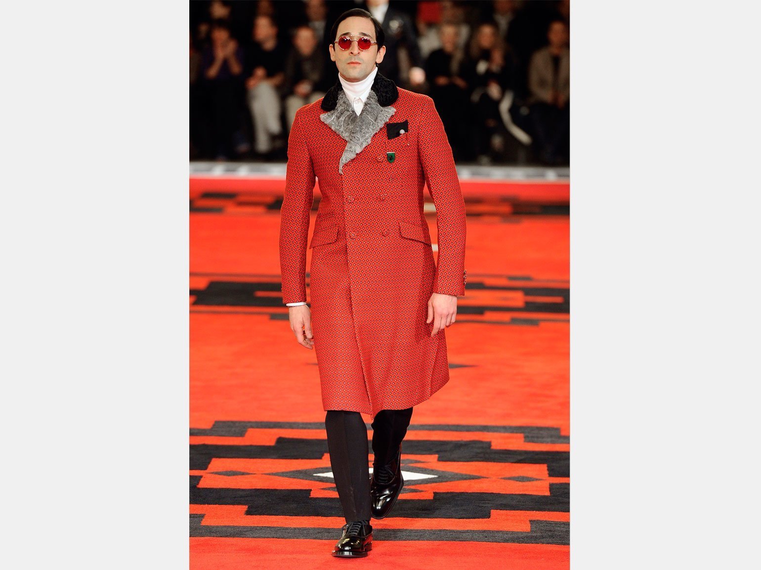 Актёр Эдриан Броуди на показе Prada в красном пальто с каракулем и в красных очках