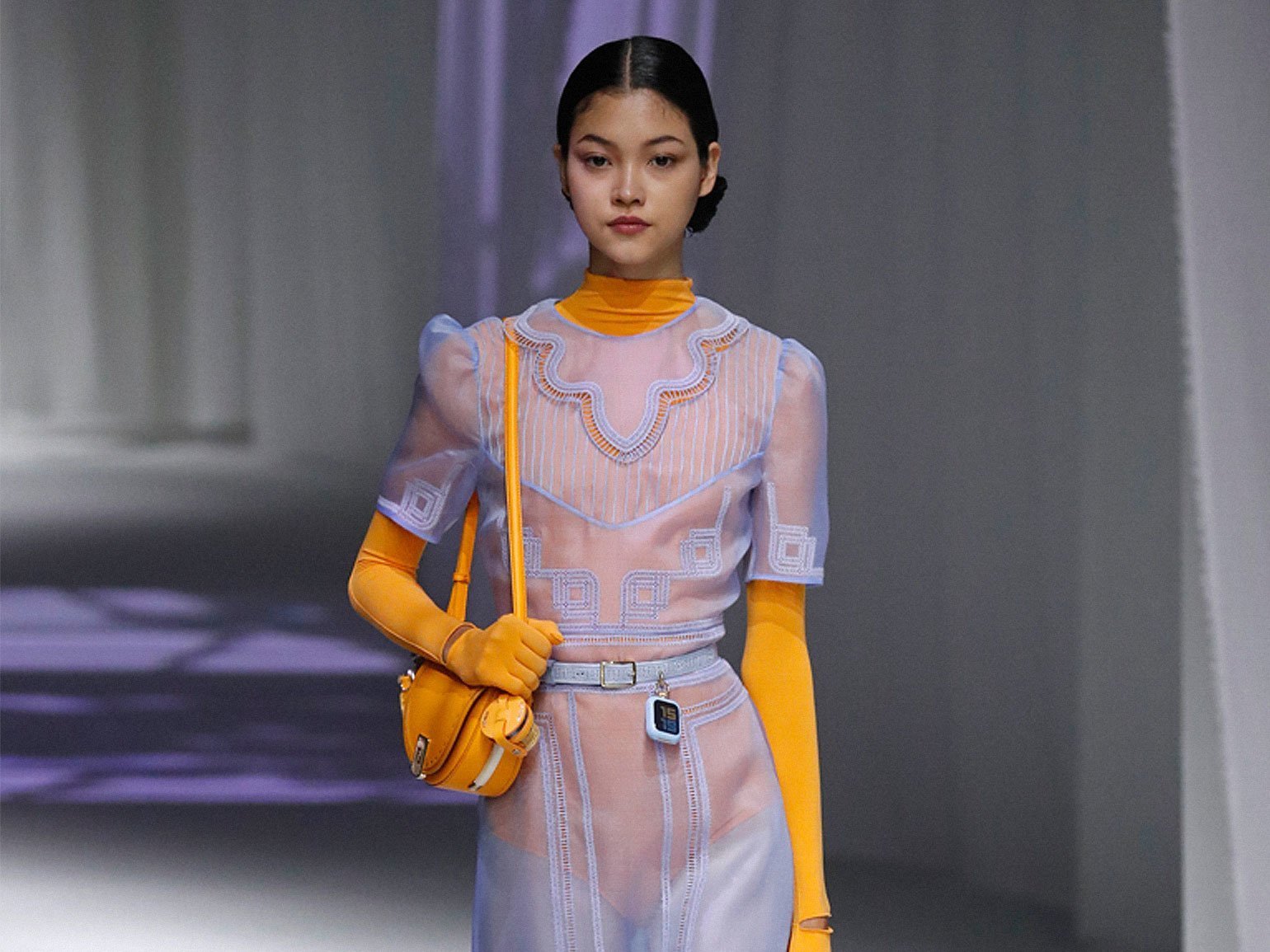 модель идёт по подиуму на показе Fendi Milan Fashion Week Spring/Summer 2021 в оранжевом боди и голубом полупрозрачном платье с оранжевой сумкой