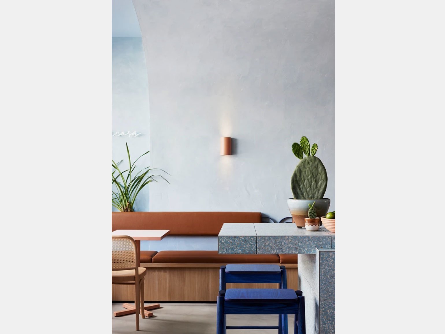 интерьер кафе в минималистичном стиле с голубыми стенами, синими стульями и коричневым диваном