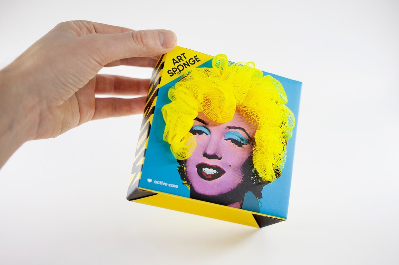 Дизайн упаковки мочалок для тела. На голубой коробке изображена Мэрилин Монро, а мочалка имитирует её волосы