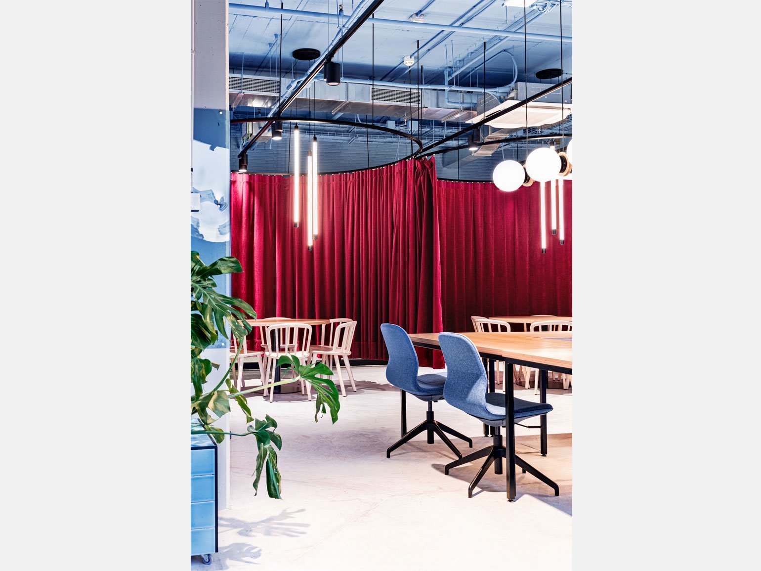 дизайн пространства коворкинга с голубыми стенами, красными шторами для отделения приватного пространства и серым бетонным полом
